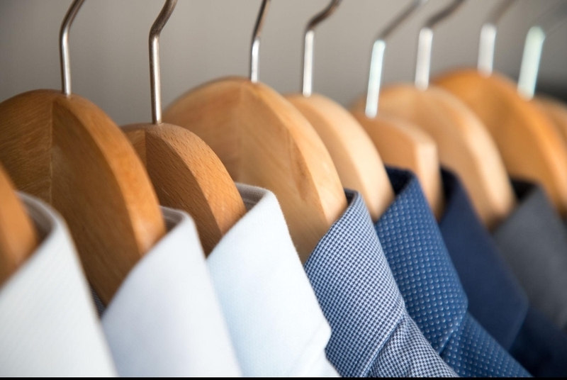 Neatly pressed shirts on wooden hangers